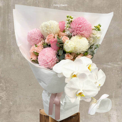Orchid Joy bouquet featuring white orchids, soft pink roses, and peach blooms, perfect for graduation celebrations.