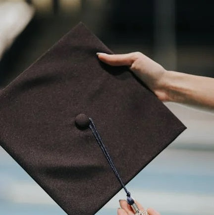 Graduation cap being held by hand, symbolizing achievement and celebration, perfect for graduation-themed flower arrangements.