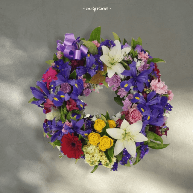 Iris Bloom wreath featuring purple, white, yellow, and red flowers, symbolizing warmth and sympathy.