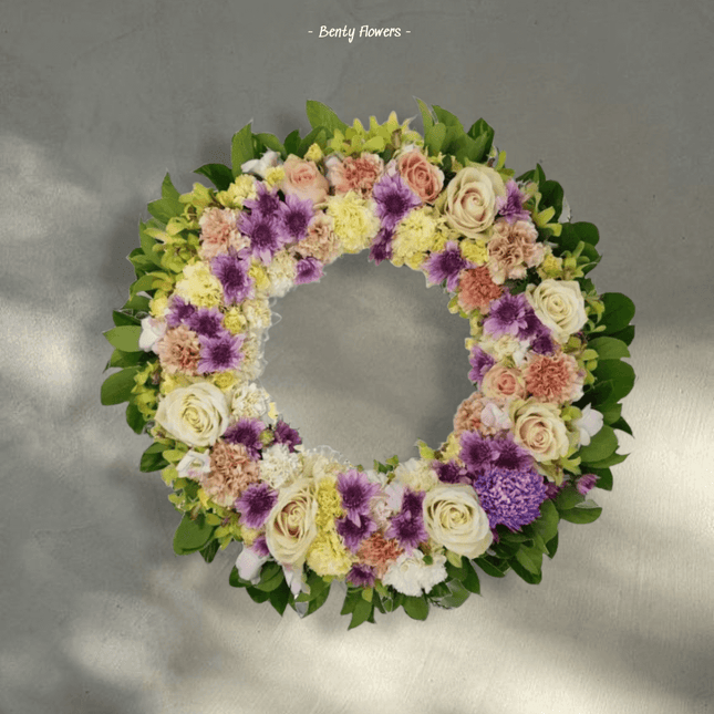 Grace Wreath featuring soft-toned roses and seasonal blooms, symbolizing sympathy and remembrance.