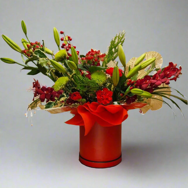 Radiant Red Elegance Bouquet with Red Roses, Lilies, and Seasonal Greenery in a Red Vase