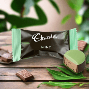 Mint chocolate from Chocolatier, featuring a smooth green chocolate piece, surrounded by chocolate squares and leaves.