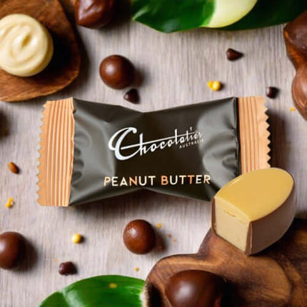 Chocolatier Australia Peanut Butter chocolate on wooden surface surrounded by assorted chocolates.