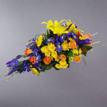 Radiant Harmony floral arrangement with yellow lilies, orange roses, purple iris, yellow chrysanthemums, and lush greenery.