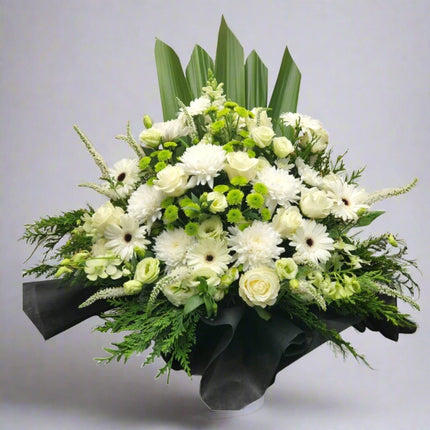 Serene Reflection standing spray with white roses, white gerberas, white chrysanthemums, green button mums, and lush greenery