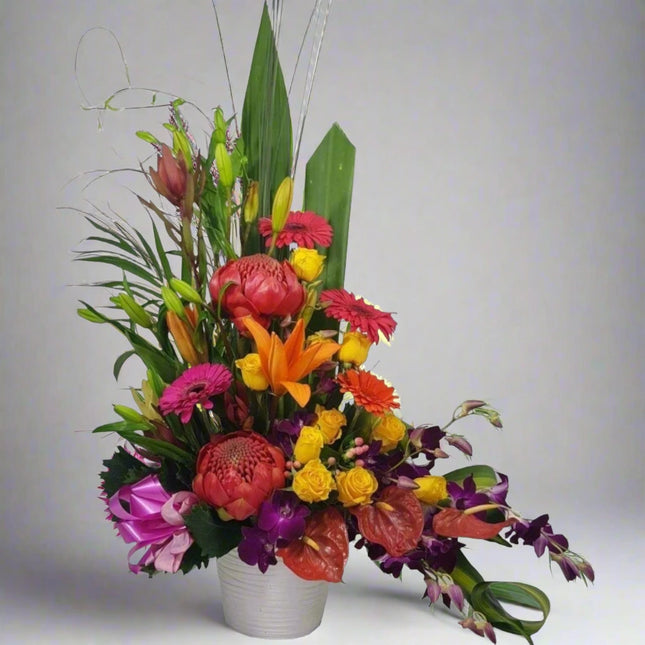 Tropical Fusion – Vibrant Floral Arrangement with orange lilies, pink gerberas, purple orchids, and yellow roses.