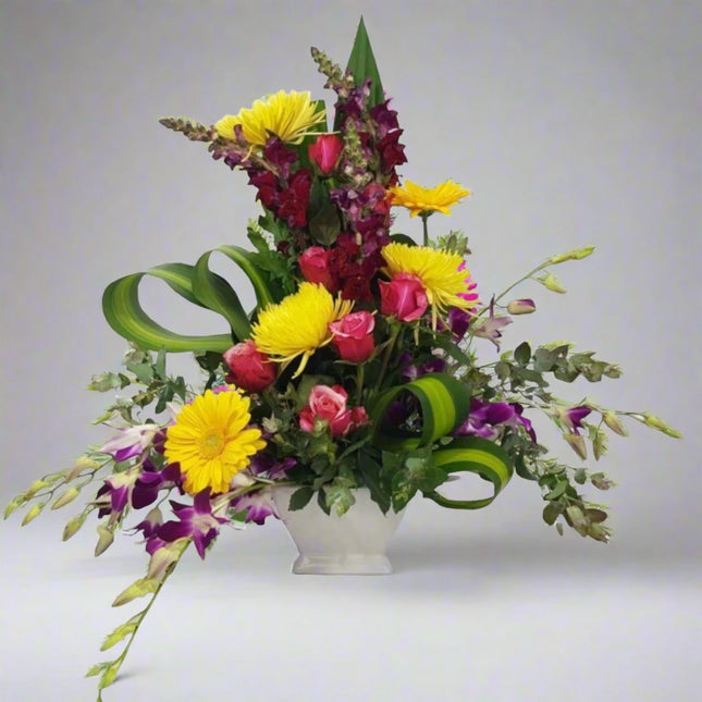 Sunshine Symphony – Bright Floral Arrangement with yellow gerberas, red roses, purple orchids, and snapdragons.