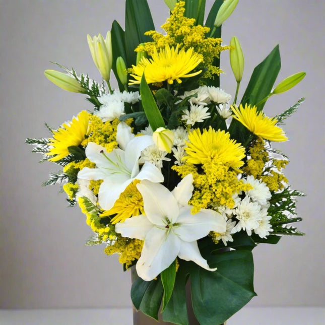 Sunny Delight – Yellow and White Floral Arrangement with white lilies, yellow chrysanthemums, goldenrods, and white daisies.