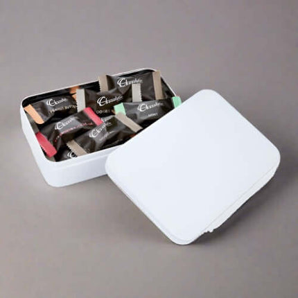 Elegant white tin filled with assorted chocolates, showcasing a delightful selection of flavors and colors.