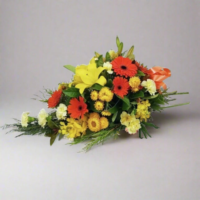 Sunset Bliss floral arrangement with yellow lilies, orange gerberas, yellow chrysanthemums, and lush greenery.