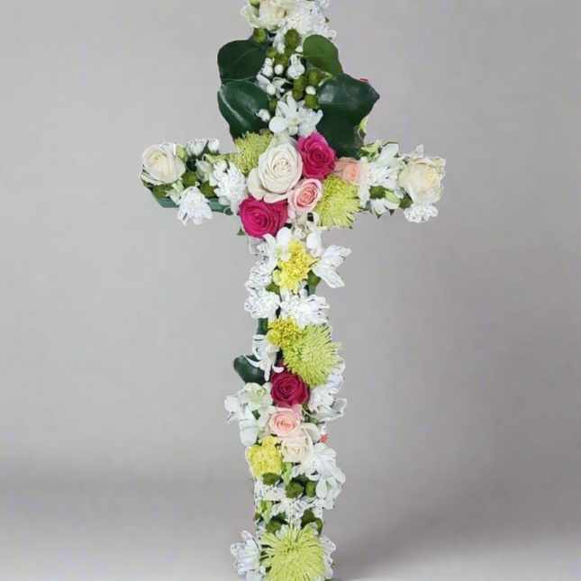 Eternal Faith cross floral arrangement with white roses, pink roses, green chrysanthemums, white lilies, and lush greenery.