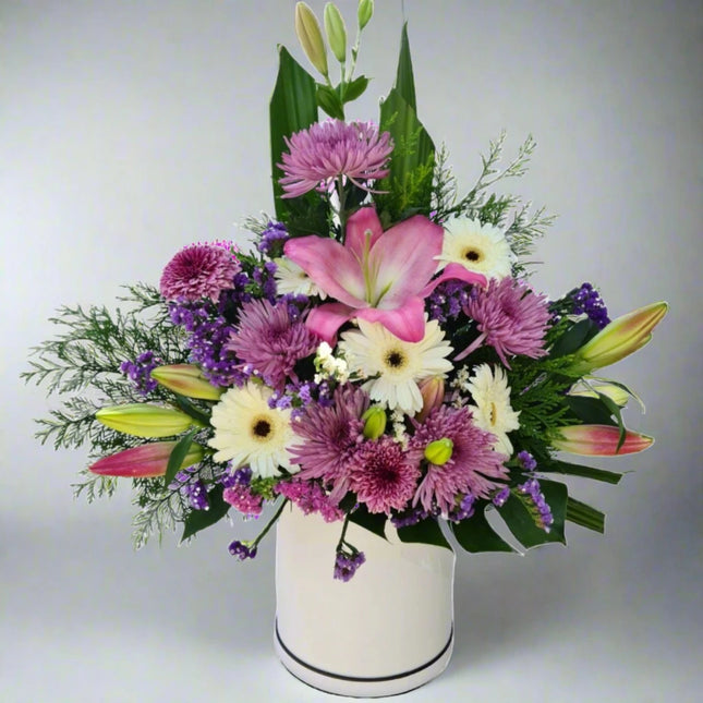 Lavender Bliss vase arrangement with pink lilies, white gerberas, purple chrysanthemums, and lush greenery.