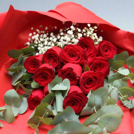 Romantic Red Rose Bouquet featuring a dozen red roses, eucalyptus leaves, and baby's breath, elegantly wrapped in red paper.