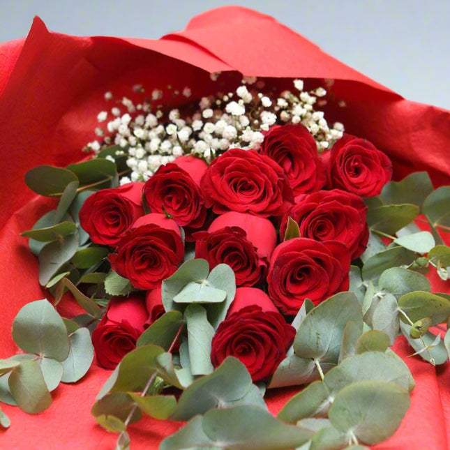 Romantic Red Rose Bouquet featuring a dozen red roses, eucalyptus leaves, and baby's breath, elegantly wrapped in red paper.