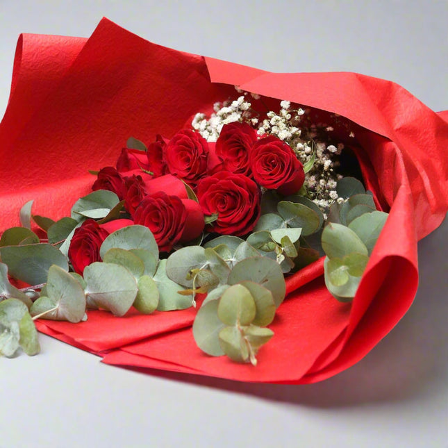 Beautiful Romantic Rose Bouquet featuring vibrant red roses, aromatic eucalyptus, and delicate baby's breath, elegantly wrapped in red paper for a stunning presentation.