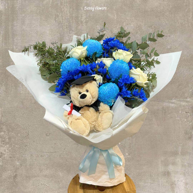 Elegant graduation bouquet with blue chrysanthemums, white roses, and a graduation teddy bear.