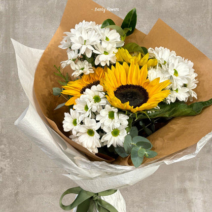 Elegant sunflower bouquet with fresh greenery, wrapped in premium beige and white paper, tied with a green ribbon, perfect for celebrations or gifting.