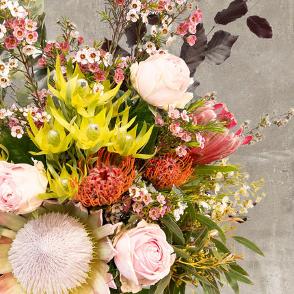 Close-up of Native Elegance Bouquet showcasing vibrant King Protea, soft pink Roses, and delicate seasonal flowers.