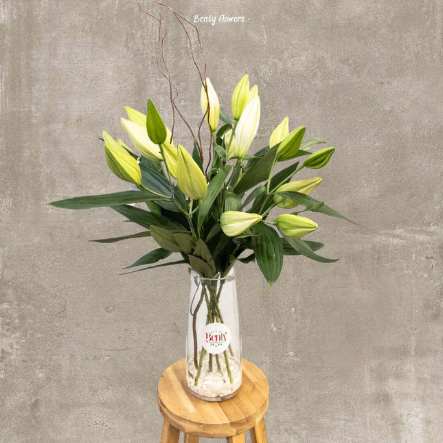 Elegant white Oriental lily vase arrangement on wooden stool, perfect for delivery in Melbourne.