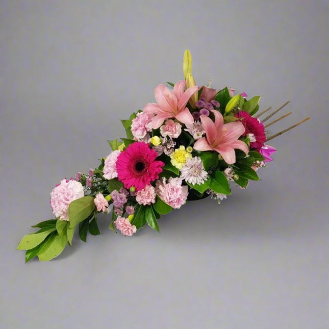 Blushing Elegance floral arrangement with pink lilies, hot pink gerberas, pink carnations, mauve chrysanthemums, and lush greenery.