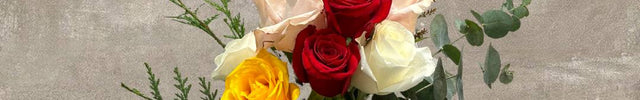 Bouquet of mixed roses with eucalyptus on a wooden stand.