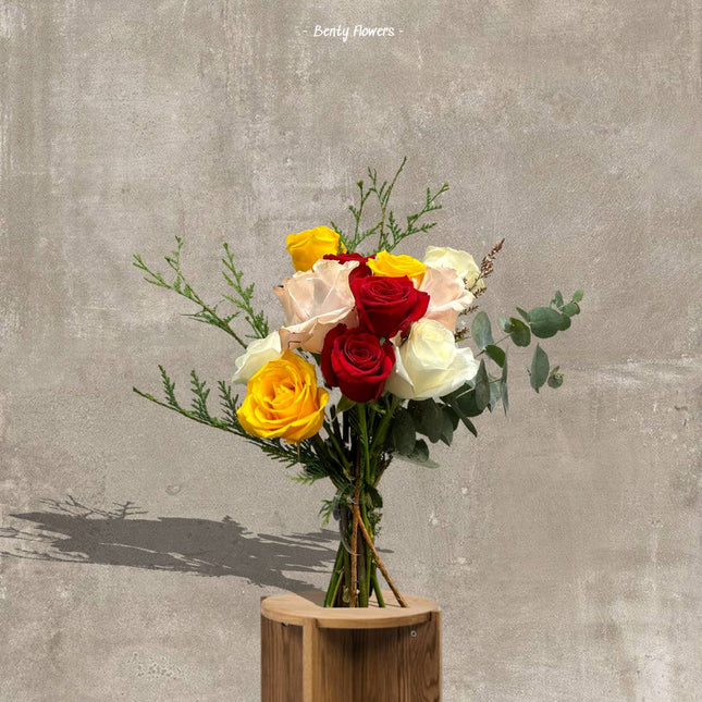 Bouquet of mixed roses with eucalyptus on a wooden stand.