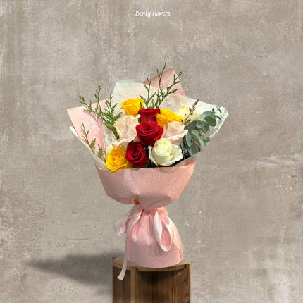 Top view of mixed roses bouquet in pink wrapping paper.