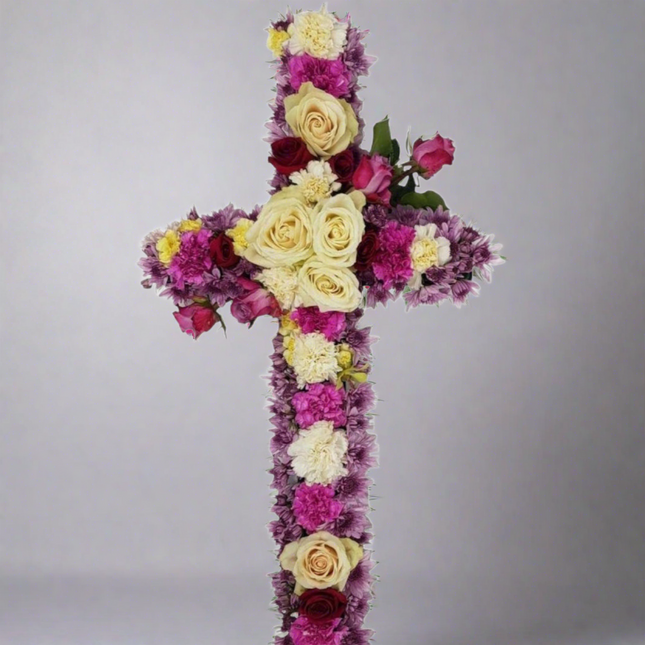 Heavenly Grace cross floral arrangement with white roses, red roses, pink carnations, purple chrysanthemums, and lush greenery