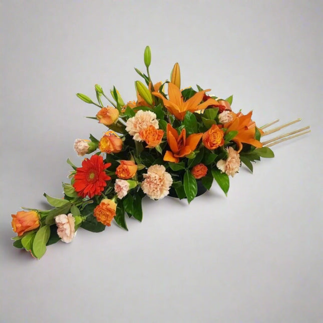 Harvest Glow floral arrangement with orange lilies, red gerberas, peach carnations, orange roses, and lush greenery